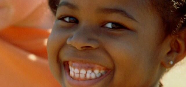 A black girl smiles, showing off white teeth